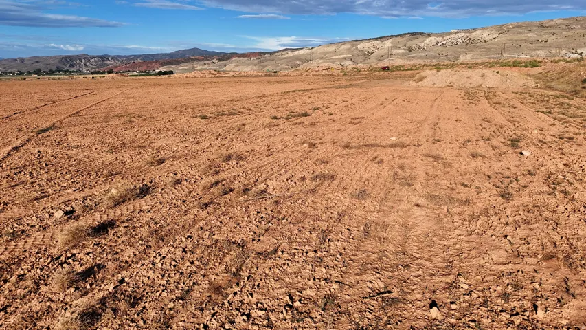 Expansive open lot featuring a clear, level terrain with distant mountainous scenery