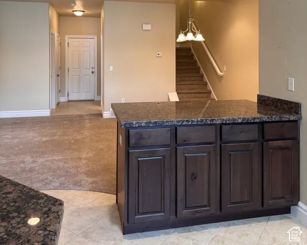 Kitchen island featuring dark wood-finish cabinetry and a stone-finish countertop