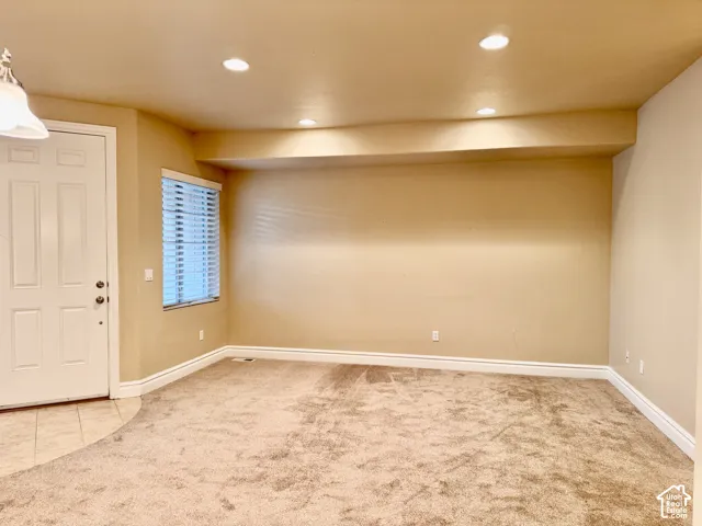 Neutral tone wall paint, recessed ceiling lighting, light-colored carpeting, white trim, and a window with blinds