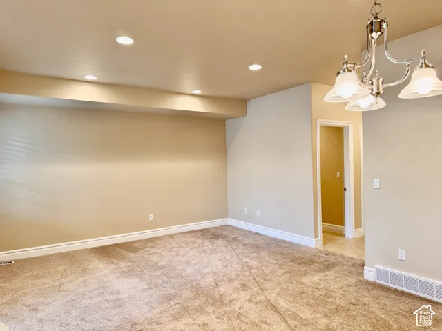 Recessed ceiling lighting, textured wall finish, plush carpet flooring, traditional chandelier fixture, and white baseboards