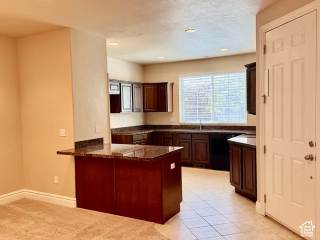 Kitchen featuring dark wood cabinetry, L-shaped countertop, recessed lighting, and tile flooring