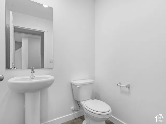 Pedestal sink, wall-mounted mirror, polished chrome faucet, white toilet