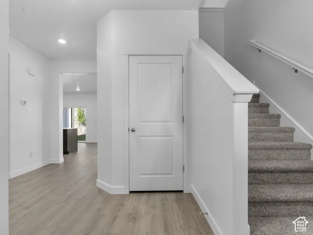 Recessed lighting, wood-finish flooring, carpeted staircase, white railing, and white interior doors