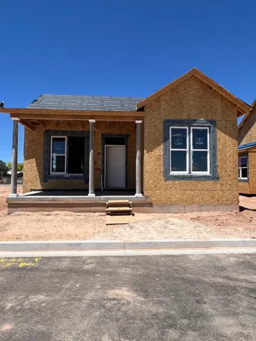 Front porch with support columns, new construction with exterior sheathing, and a paved street with curb
