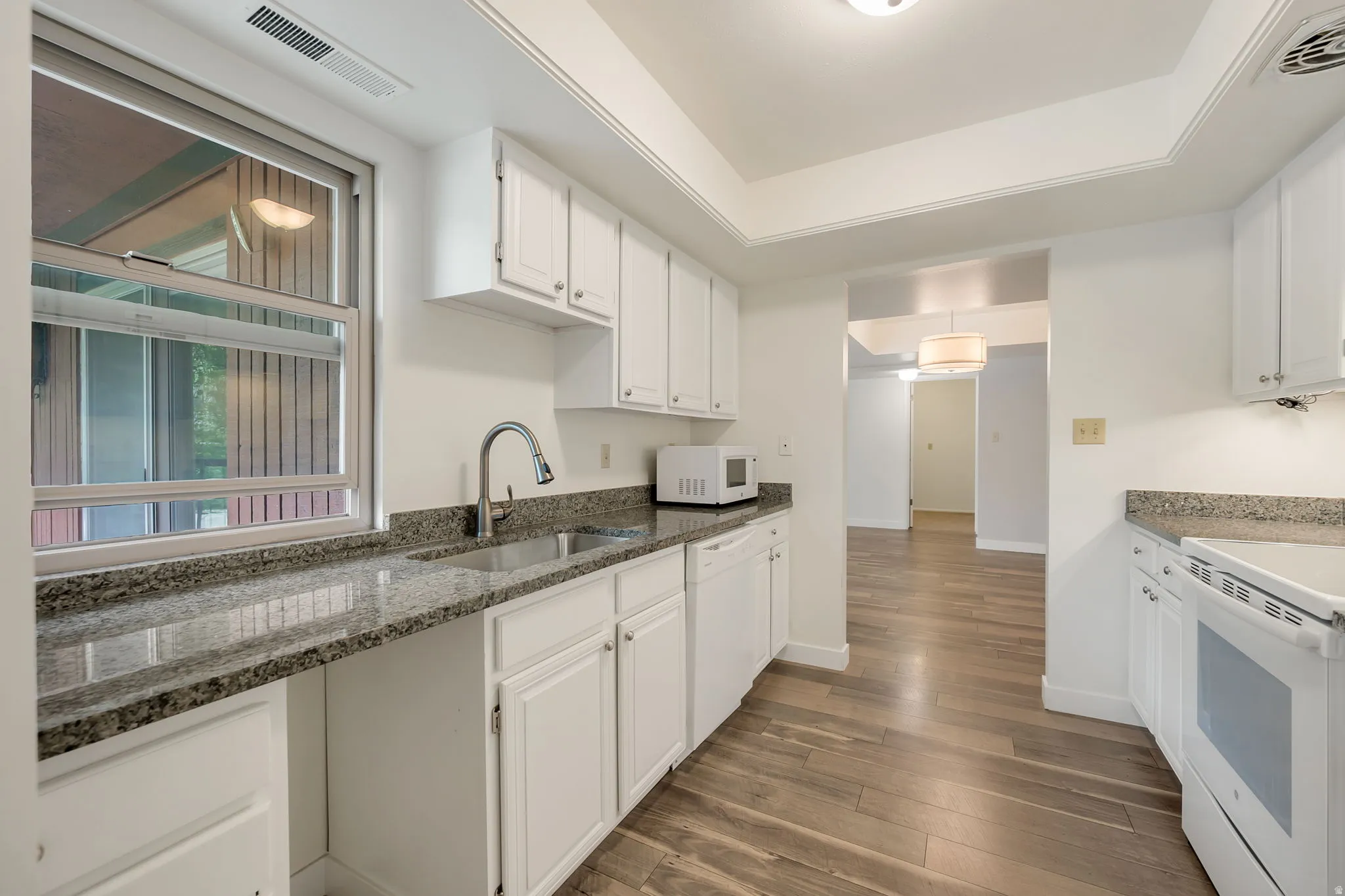 Galley kitchen with white cabinetry. Granite Countertops. Pantry.