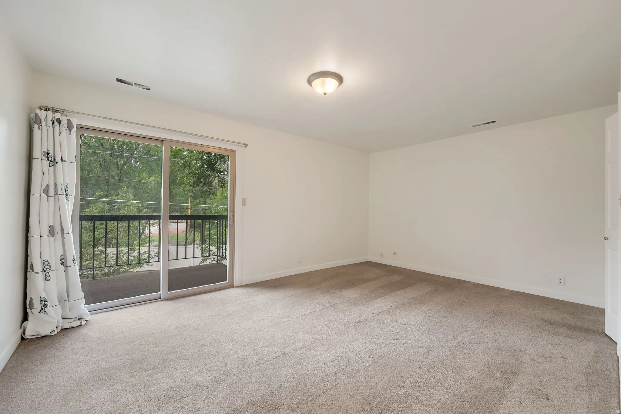 Primary bedroom with ensuite bathroom. Sliding glass doors opening to a private balcony. Walk-in closet.