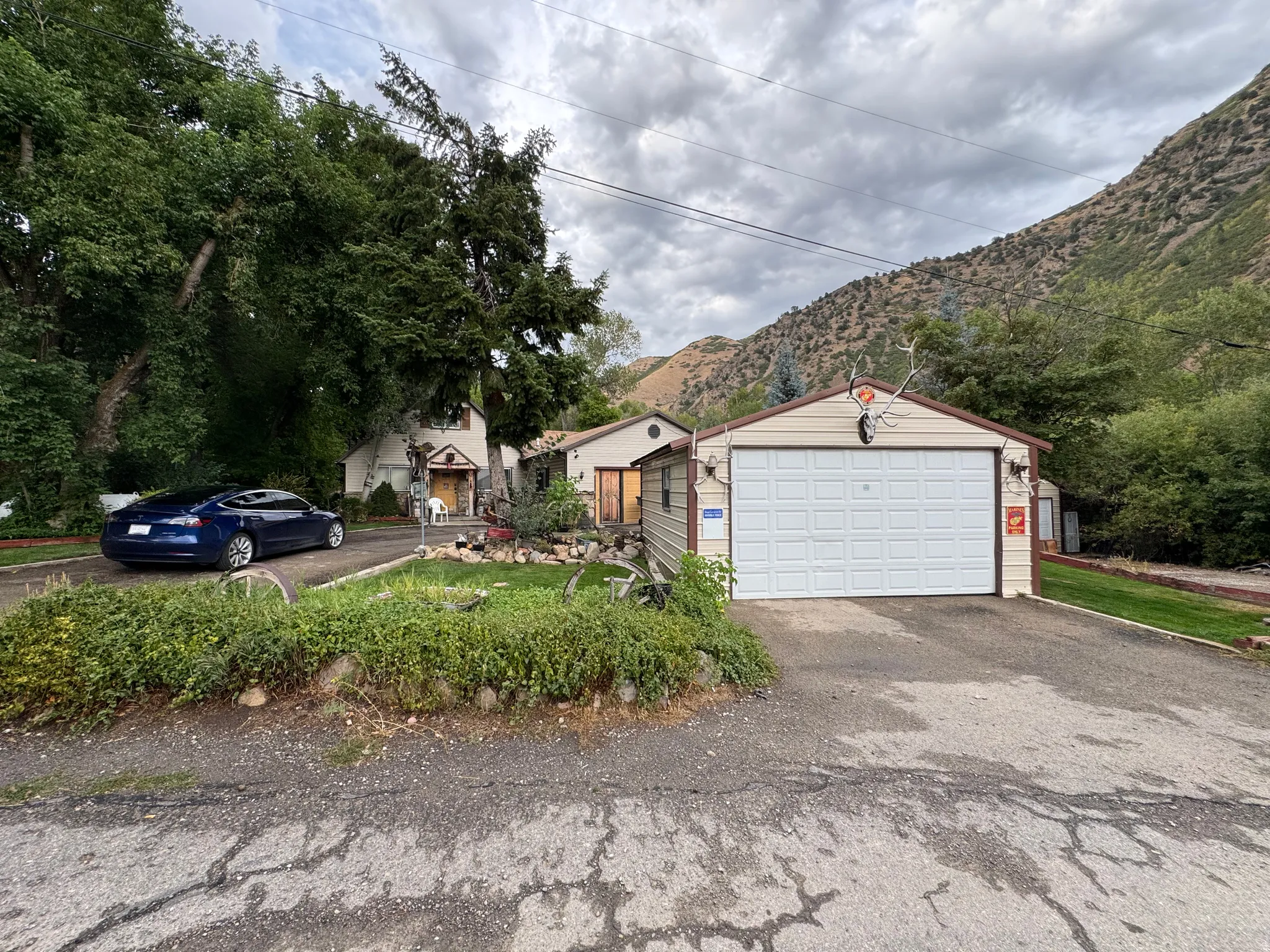 Detached garage with a paneled door, mature trees, and a mountain backdrop