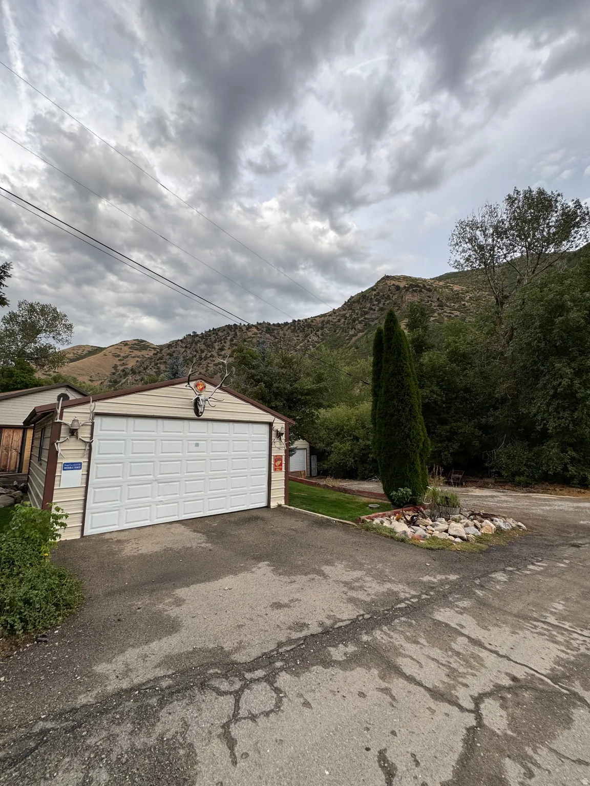 Detached garage with horizontal panel door, light-toned siding, and exterior lighting