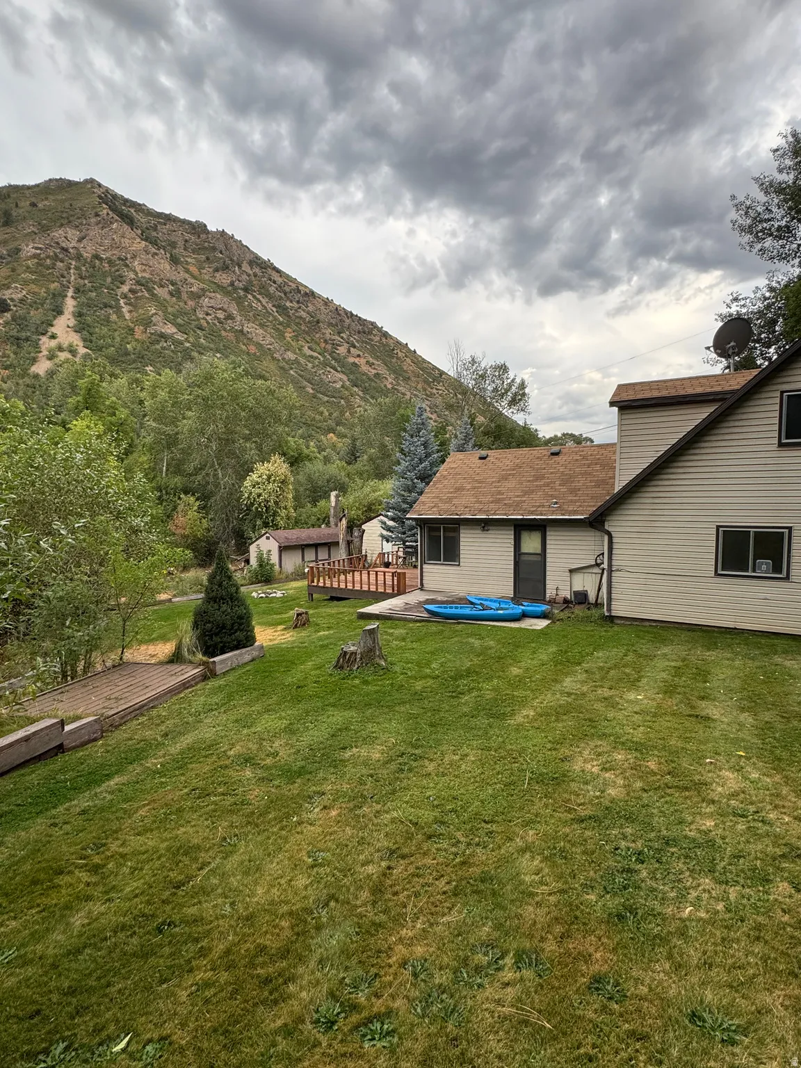 Expansive green lawn with mature trees and a mountain backdrop