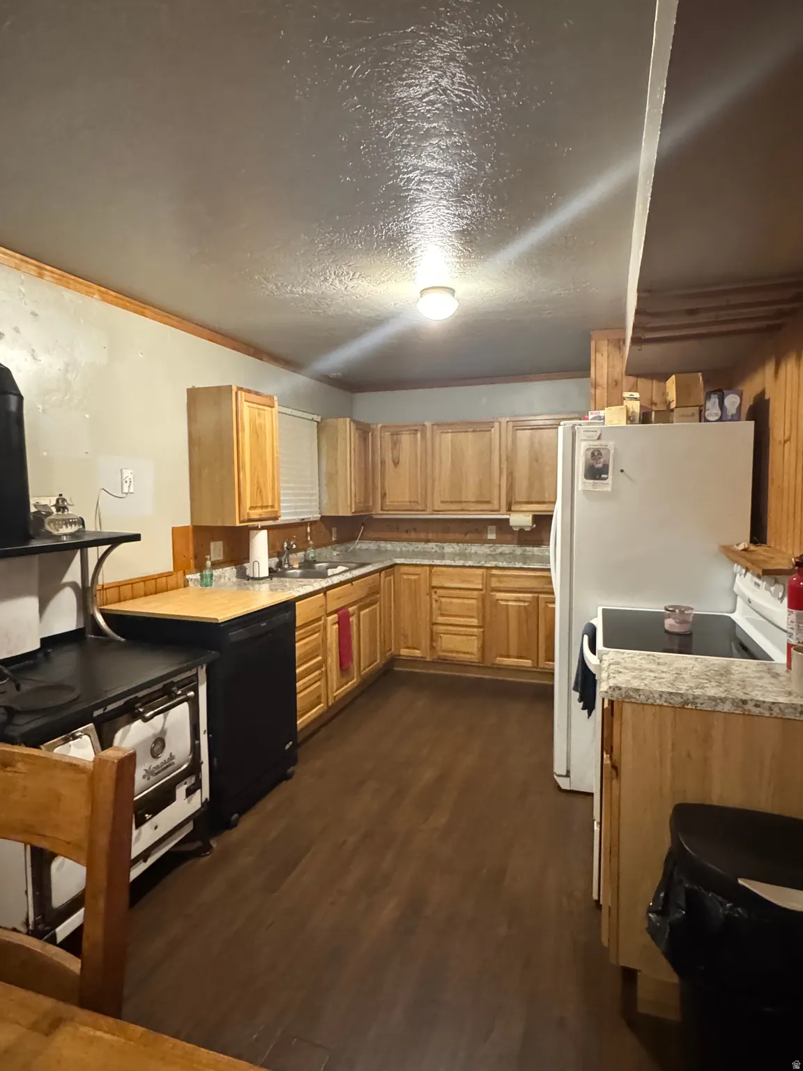 U-shaped kitchen with wood-finish flooring, natural wood cabinetry, and light-toned countertops
