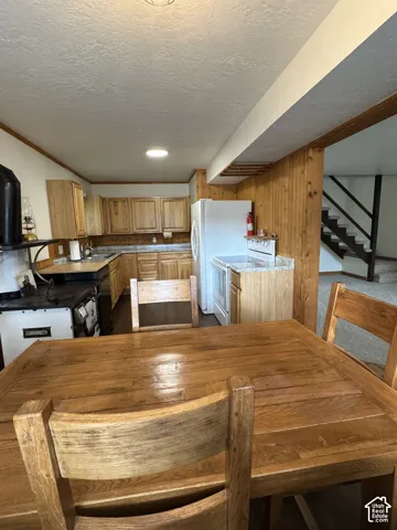 Kitchen featuring wood cabinetry, stone-finish countertops, built-in black stove, and light wood-finish wall paneling