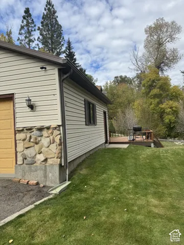 Exterior featuring horizontal siding, natural stone accents, a concrete foundation, and a rear raised deck