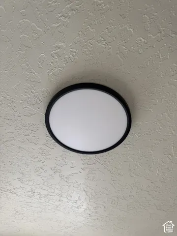 Circular flush-mount ceiling light with a matte black trim and an acrylic diffuser set against a textured ceiling finish