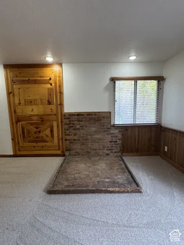 Exposed brick hearth, decorative natural wood paneling, custom-built wood door, and recessed lighting