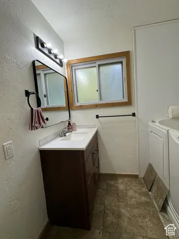 Bathroom featuring a vanity with a solid-surface countertop, rectangular undermount sink, dark wood-finish cabinetry, a framed vanity mirror, and multi-bulb wall lighting