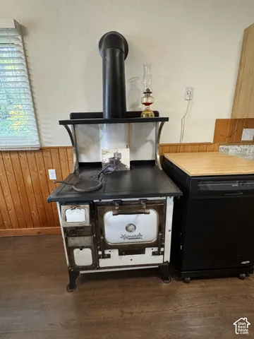 Vintage Monarch cast iron stove featuring a white enamel finish, integrated metal flue, and wood-paneled wall surround