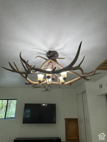 Custom antler chandelier featuring five bell-shaped glass light fixtures and a rustic metal frame