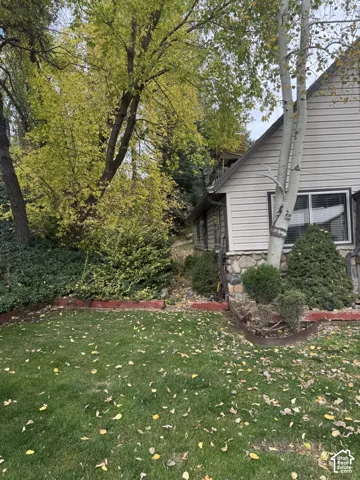 Exterior featuring stone foundation detailing, horizontal siding, and established landscaping with mature trees