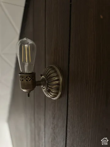 Vintage-inspired brass sconce featuring intricate filigree detailing, mounted on dark-stained vertical wood paneling