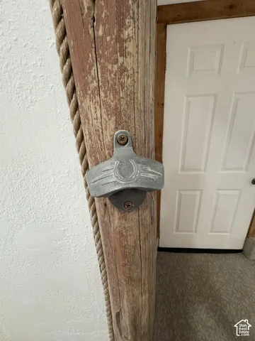Natural log post featuring a wall-mounted cast metal bottle opener and decorative rope detailing