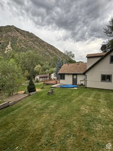 Expansive green lawn with mature trees and a mountain backdrop