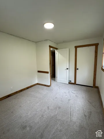Neutral carpeting, solid wood door and window trim, and interior wood-paneled door