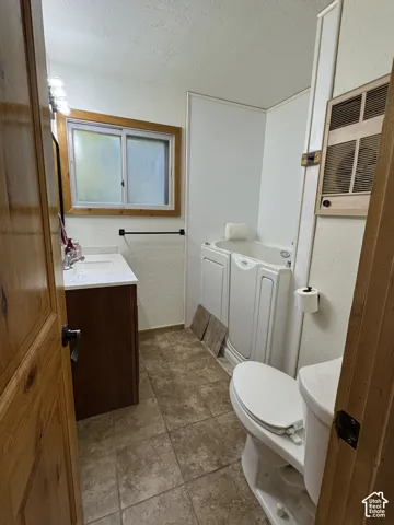 Bathroom featuring a vanity with white countertop, step-in soaking tub, tile-finish flooring, and wood-trim accents
