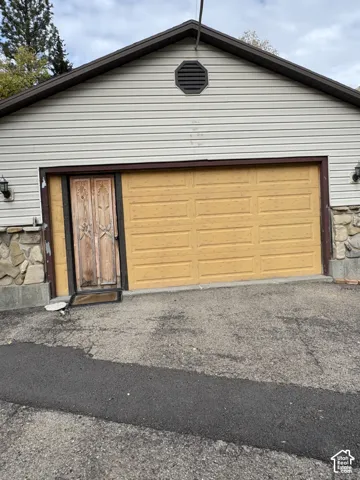 Detached structure featuring horizontal siding, natural stone veneer accents, an octagonal gable vent, and two exterior wall-mounted light fixtures