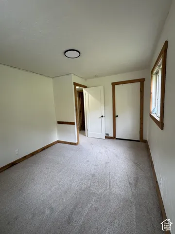 Interior room featuring neutral wall-to-wall carpeting, natural wood window and door trim, a flush-mount circular ceiling light fixture, and a built-in wall niche