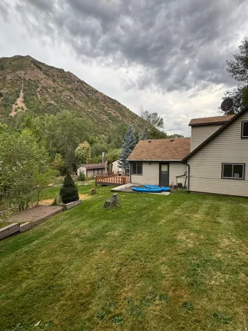 Expansive green lawn with mature trees and a mountain backdrop