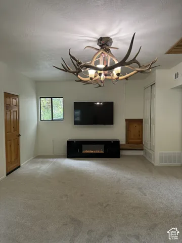 Custom antler chandelier, wall-mounted television, built-in wooden recessed shelf, and dual-panel closet doors