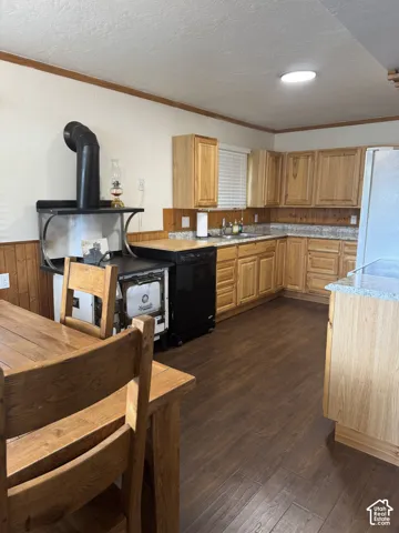 Kitchen featuring natural wood cabinetry, wood-finish flooring, stone-finish countertops, wood-panel wainscoting, and a vintage-style wood burning stove