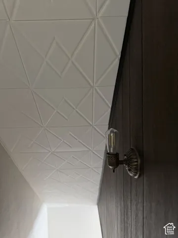 Geometric patterned ceiling treatment, vertical dark-stained wood wall paneling, and an antiqued bronze metal wall-mounted light fixture with an exposed filament bulb
