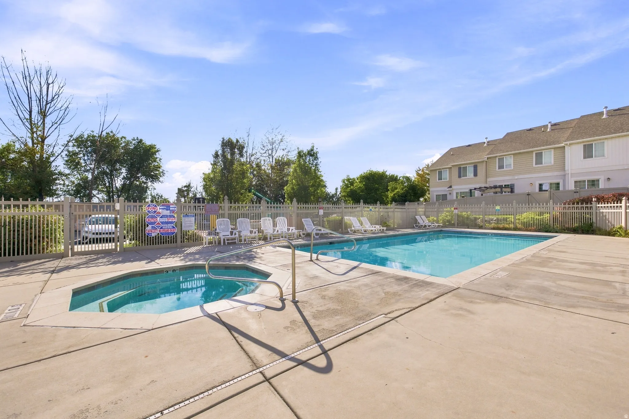 Community swimming pool and spa with concrete surround and fencing