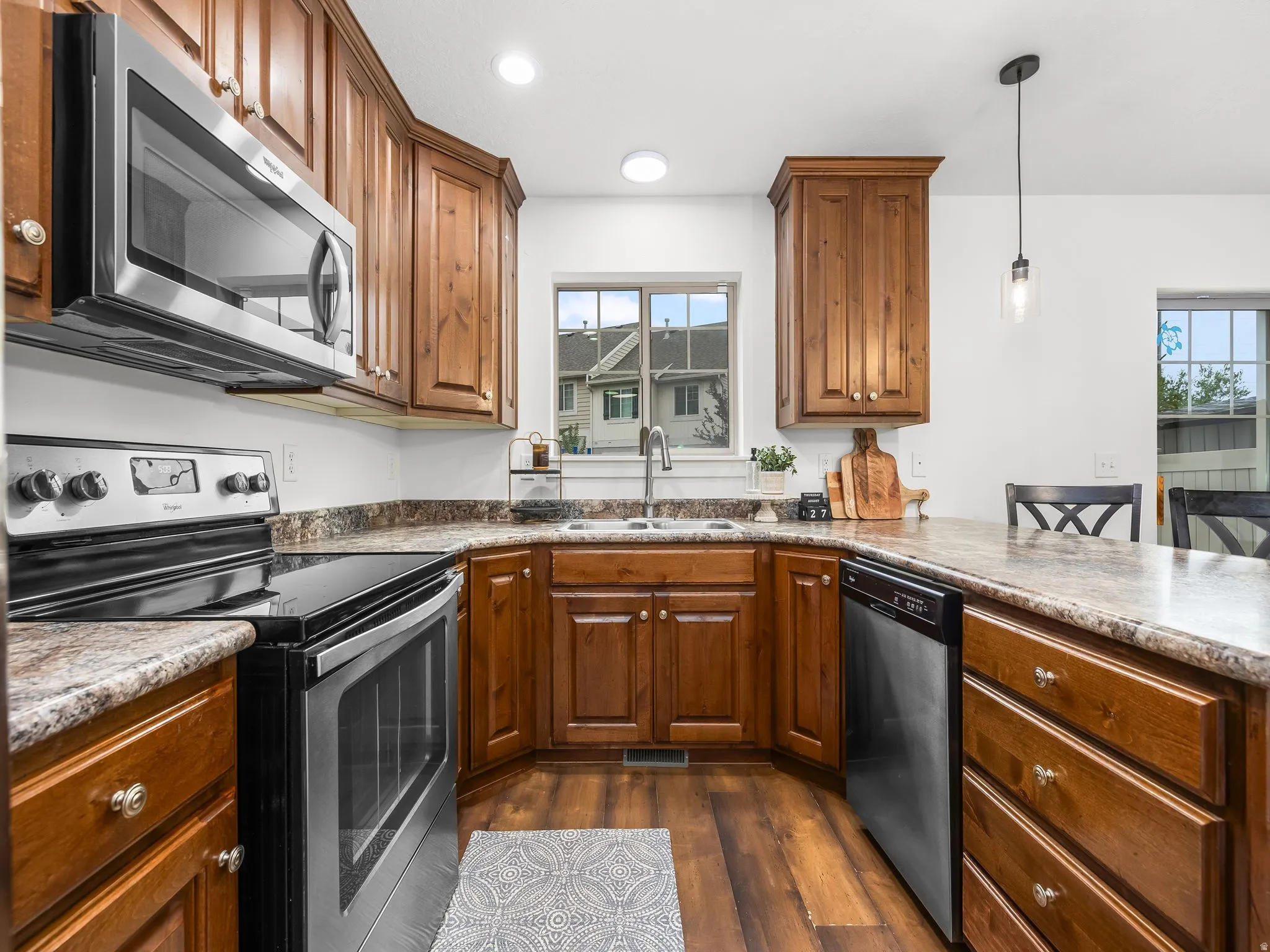Kitchen featuring wood-finish cabinetry, stainless steel appliances, a double basin sink, and recessed lighting