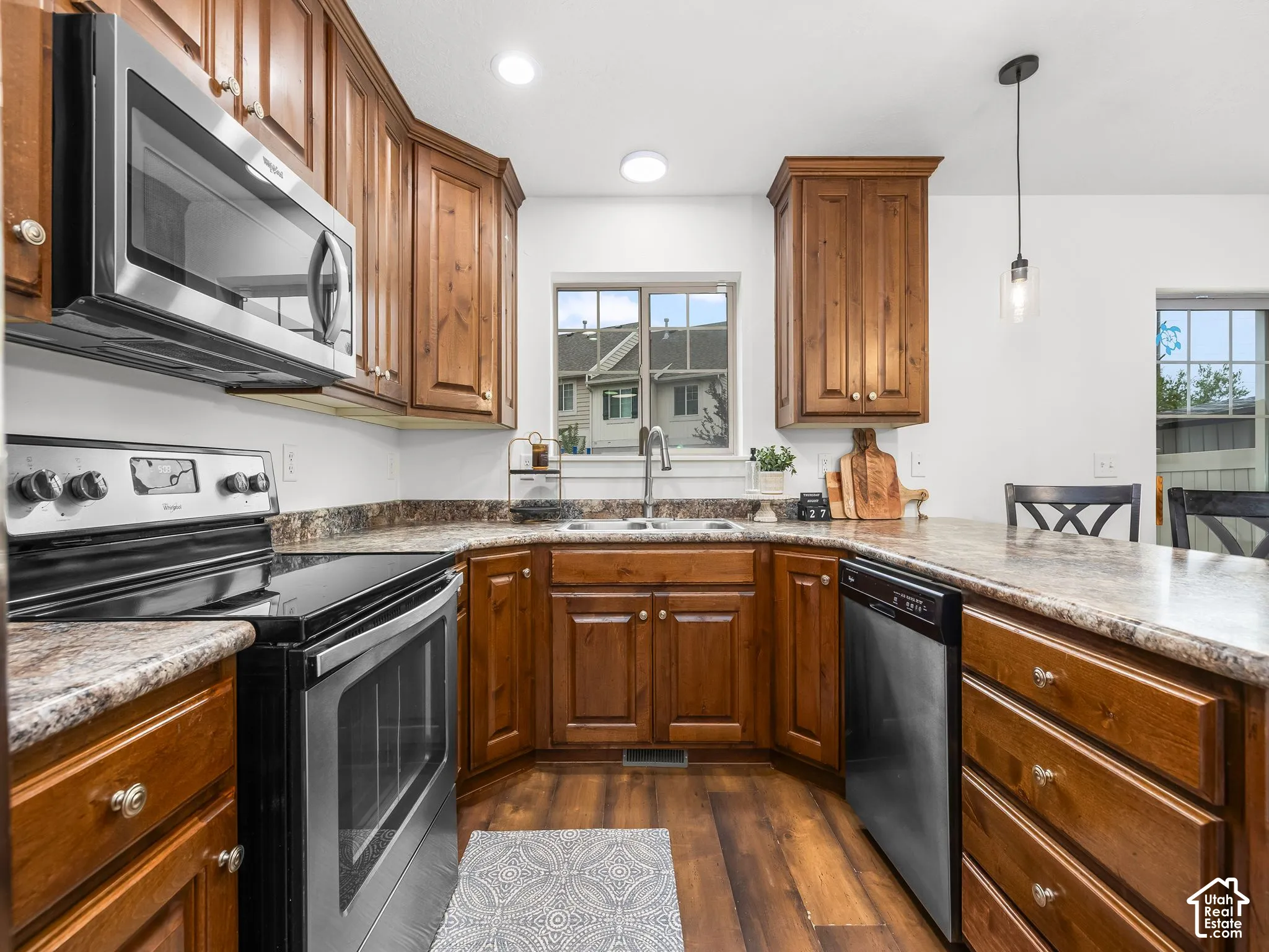 Kitchen featuring wood-finish cabinetry, stainless steel appliances, a double basin sink, and recessed lighting