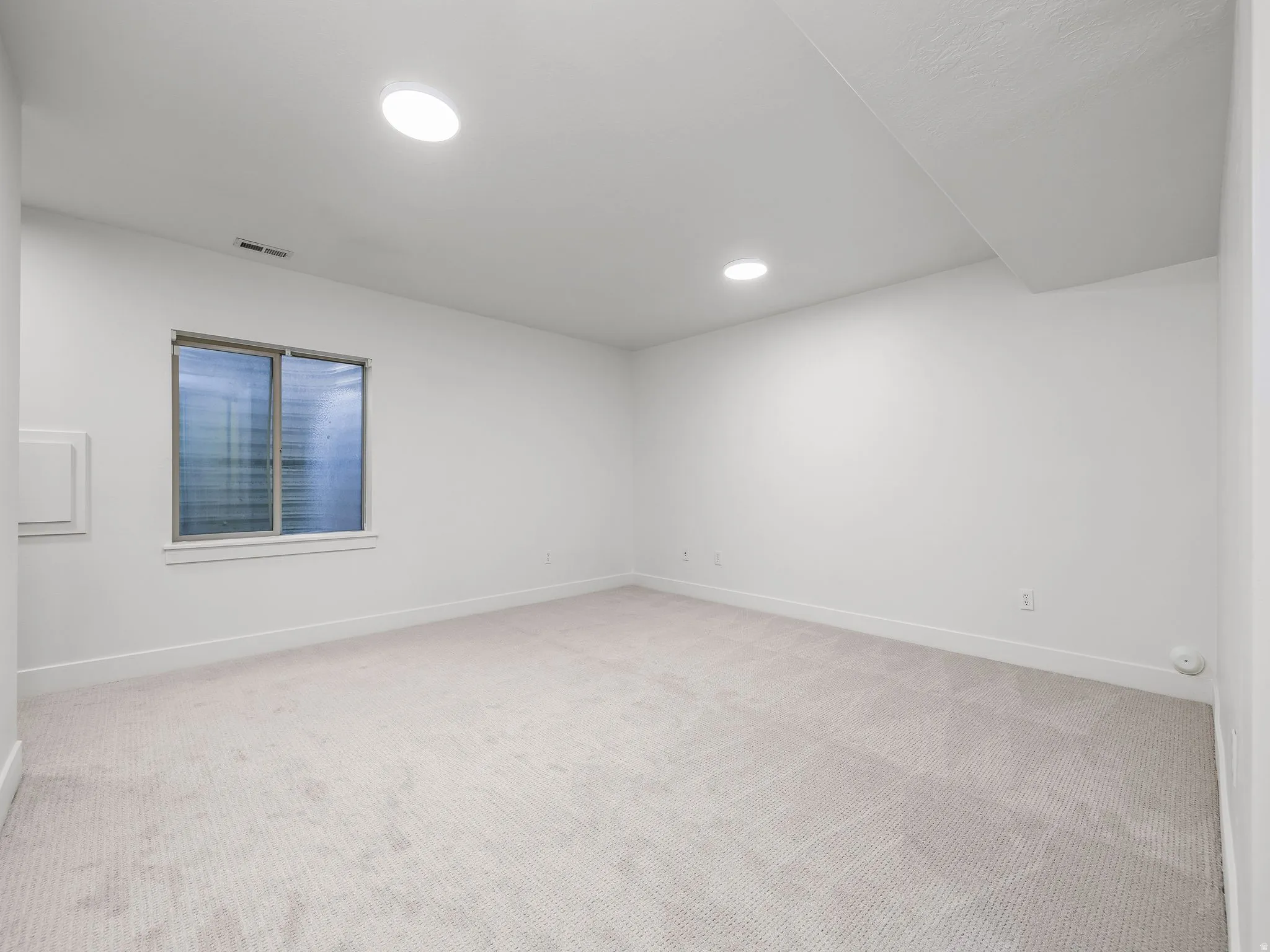 Neutral-toned carpeting, recessed lighting, and a window with blinds