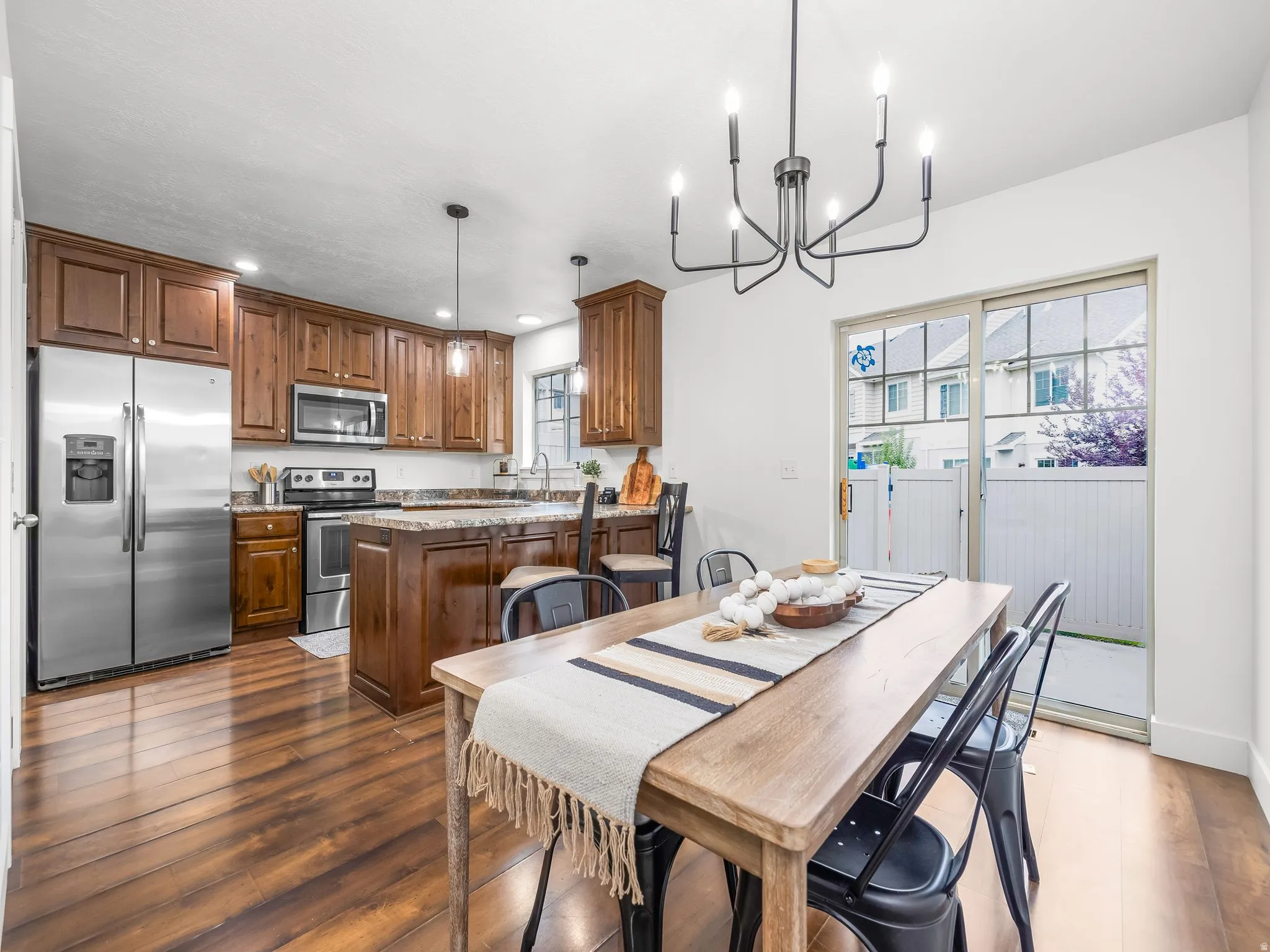 Kitchen with wood-finish flooring, stainless steel appliances, and a central island with bar seating