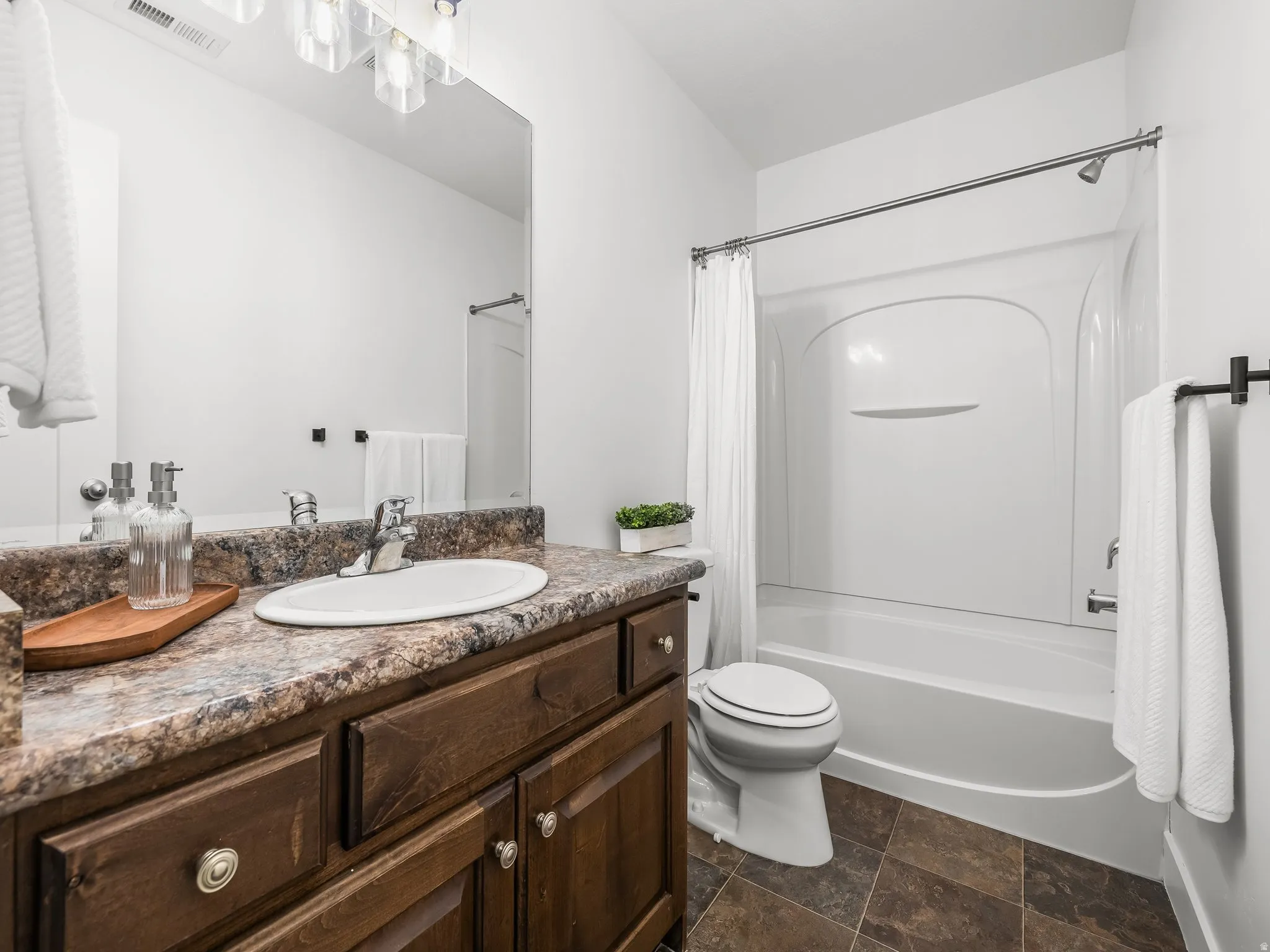 Bathroom featuring a dark wood-finish vanity, integrated sink, and an overhead light fixture