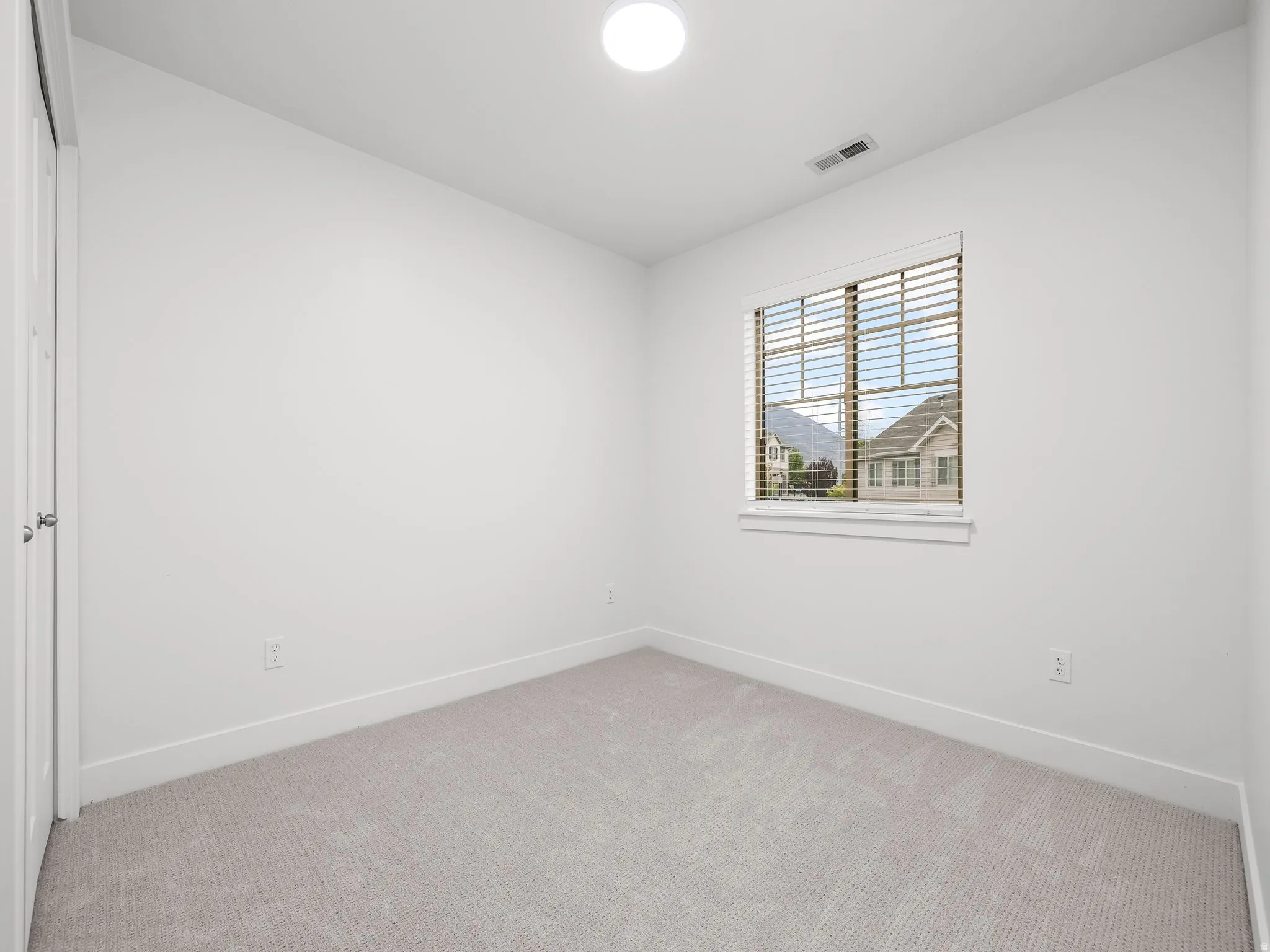 Neutral wall paint with carpeted flooring, a window with horizontal blinds, and a flush-mount ceiling light