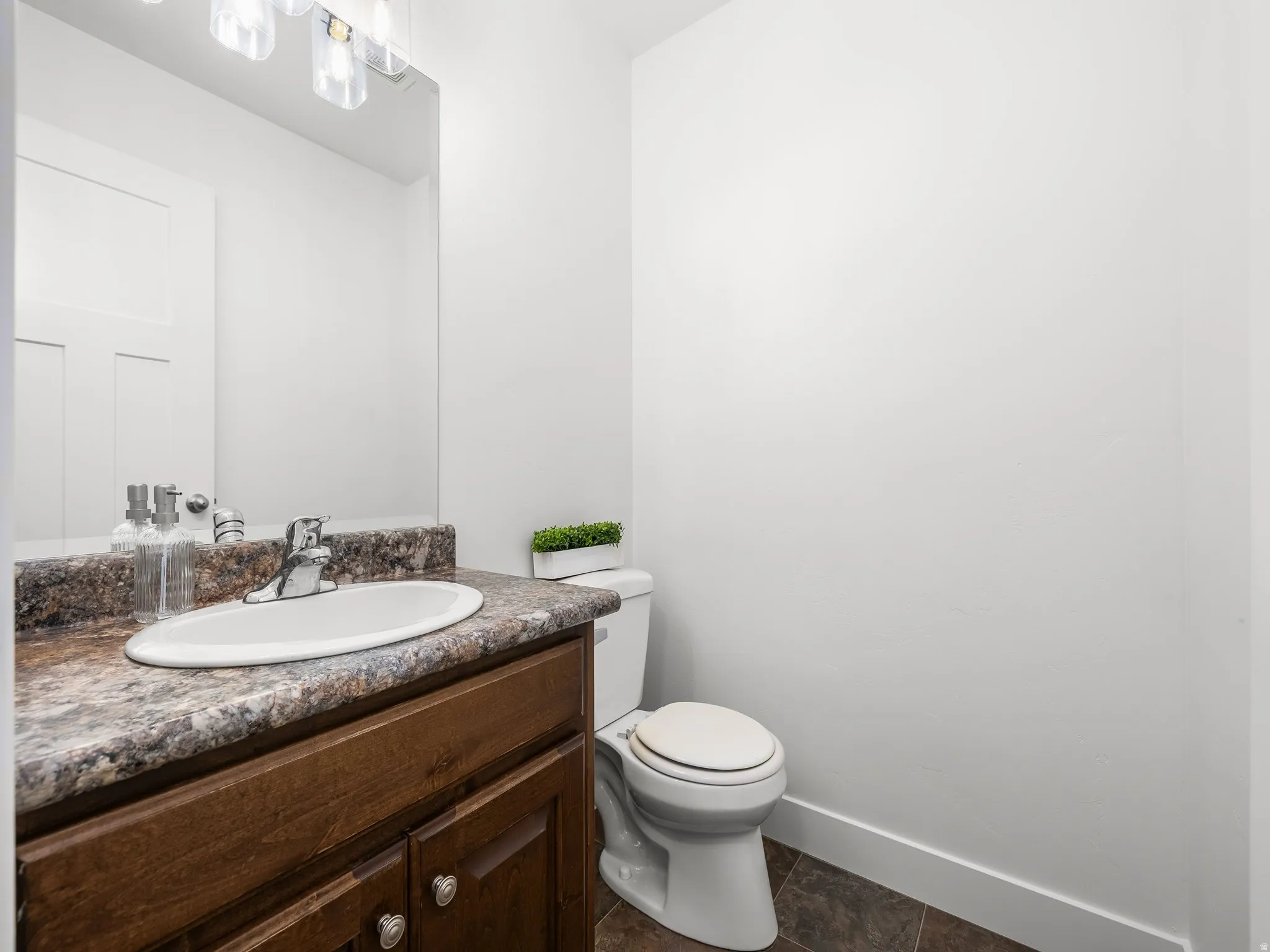 Vanity with wood-finish cabinetry, a drop-in sink, and a speckled countertop