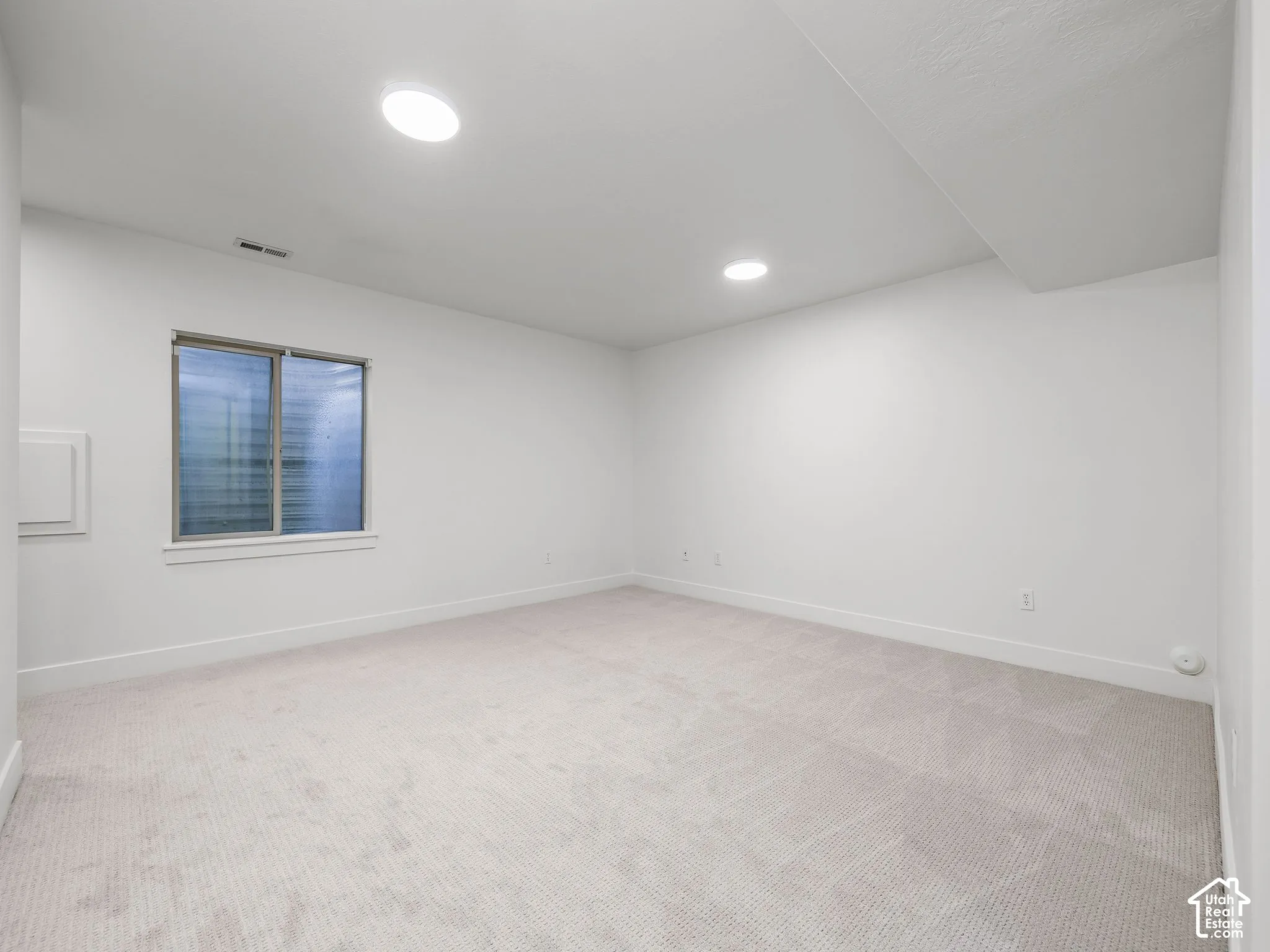 Neutral-toned carpeting, recessed lighting, and a window with blinds