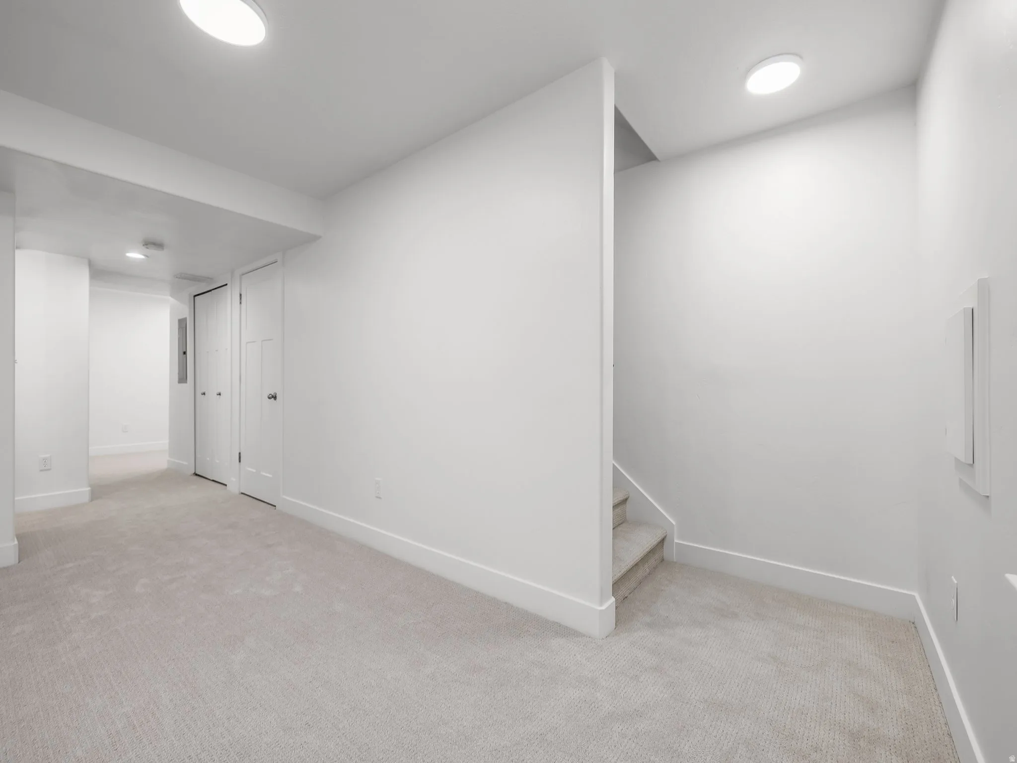 Light-colored carpeting, white baseboards, recessed lighting, and white panel doors