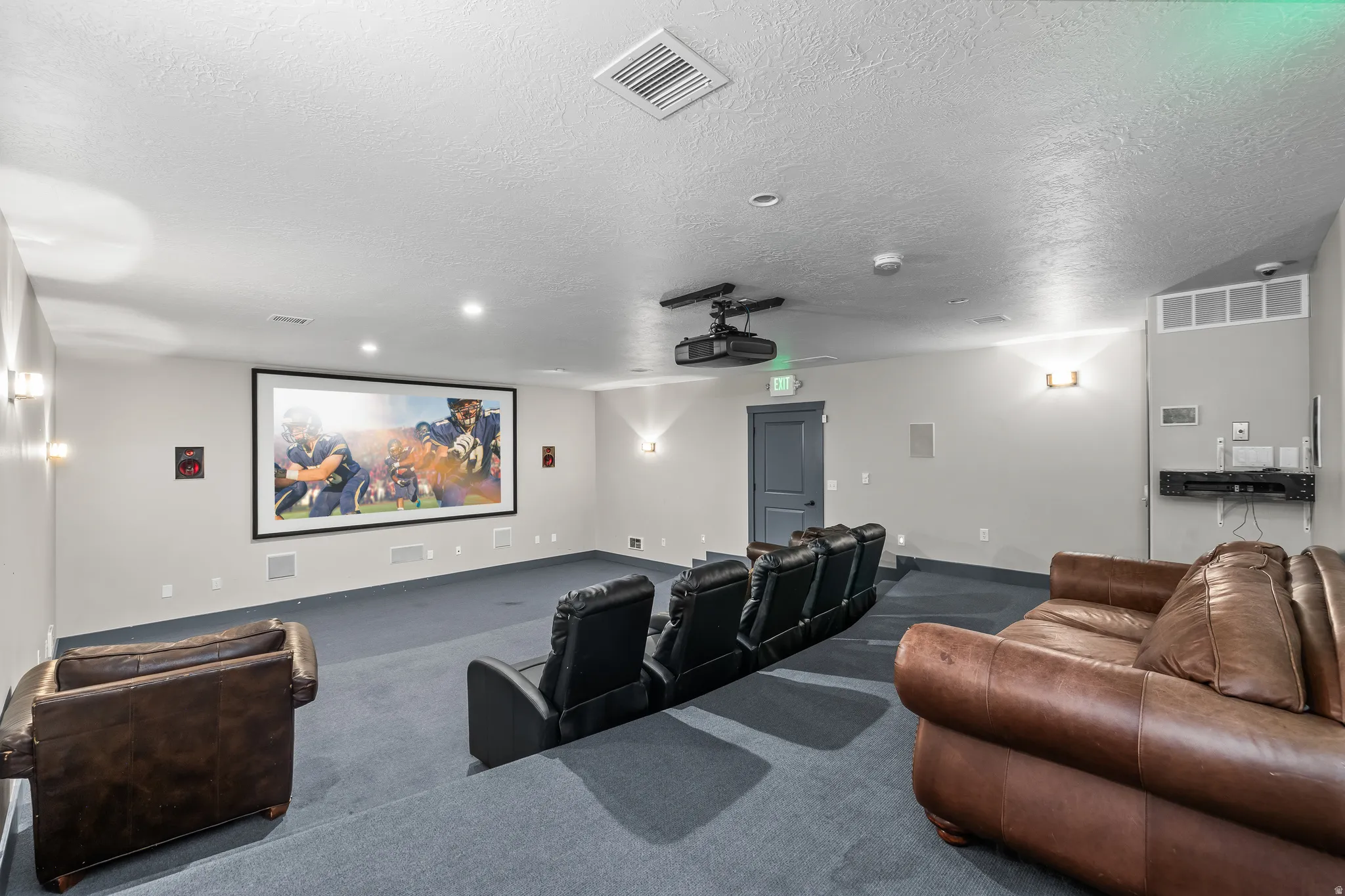 Integrated projector with large screen, built-in wall speakers, wall-mounted sconce lighting, and a multi-tiered floor design