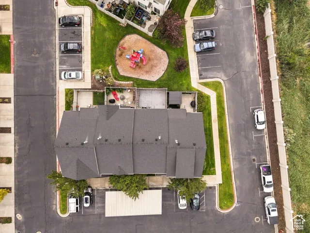 Gable roofline with multiple vent stacks, covered outdoor patios, paved parking areas, and mature trees