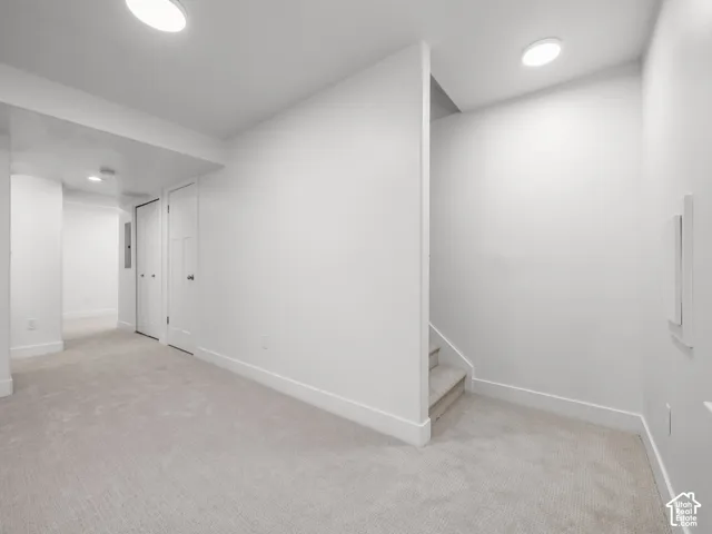 Light-colored carpeting, white baseboards, recessed lighting, and white panel doors