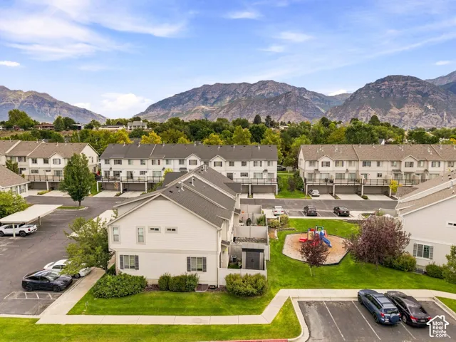 Mountain backdrop, residential community, multiple two-story townhomes, manicured green spaces, and a dedicated play area