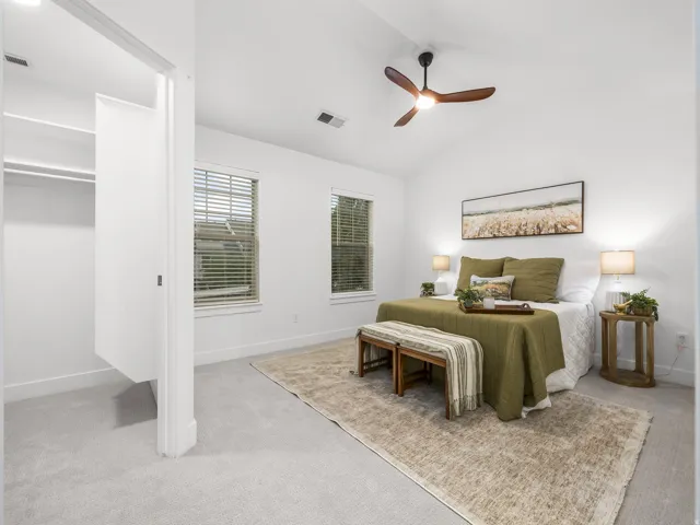 Primary bedroom with ensuite bathroom access, neutral carpeting, and abundant natural light from dual windows