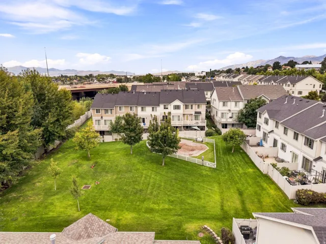Expansive green space with manicured lawn, established trees, and white picket fencing