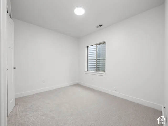 Neutral wall color, light-toned carpeting, flush-mount ceiling light, window with horizontal blinds, and white trim